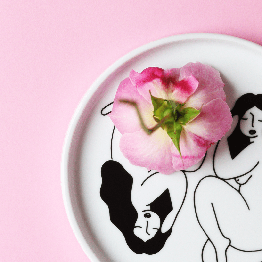 Picture of a white plate with two women painted on it in black with a pink rose depicting the best herbs for women's health