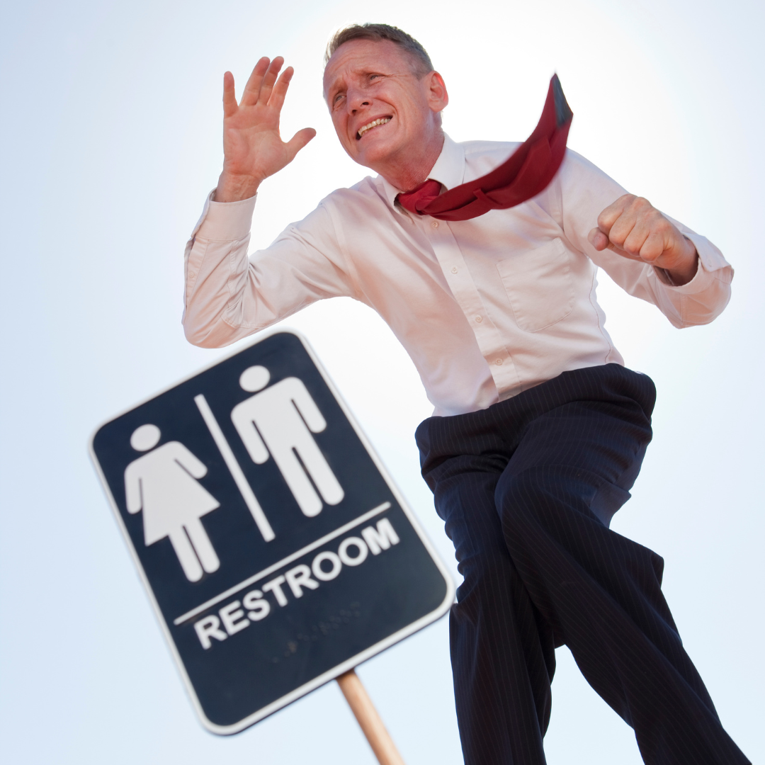 Man running past a restroom sign hoping to get to the bathroom before its to late