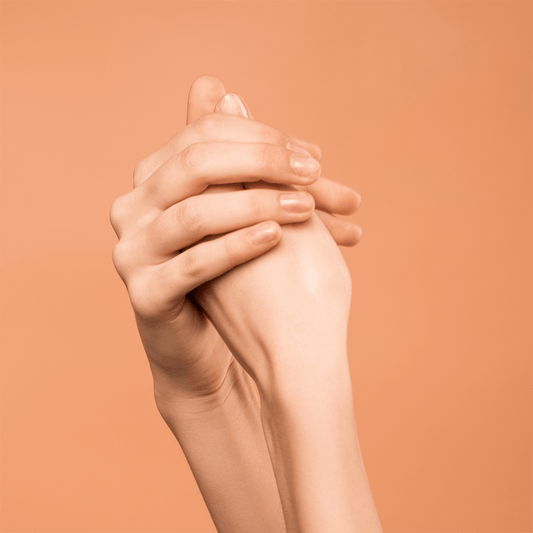 Two hands clasped together with an apricot background